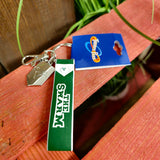 A photo of the keyring, it has a green strap with the words The Swarm on it, and two charms - a metal clip embossed with the logo and a keyring clip