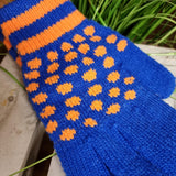 A close up of the knitted gloves showing the blue hand and finger area speckled with orange dots and stripes on the wrists