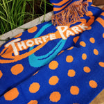A photograph of the full Thorpe Park logo in the middle of the scarf, with a blue background and surrounded by orange dots
