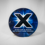 A circular sign which has a blue and black mottled background and a large X in the middle in black. The slogan "Ride on a wave of light and sound" is underneath it in white text.