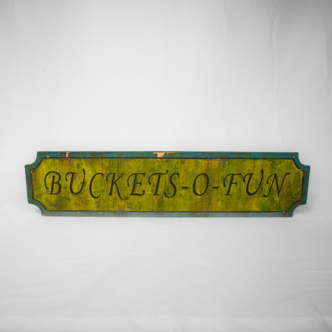 A rectangular sign with indents in each corner. The middle is a yellowy/green paint with the words Buckets-O-Fun bevelled in. The border is a teal.