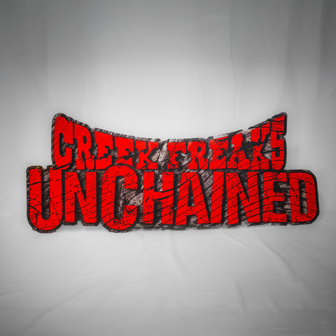 A landscape, shaped sign reading Creek Freaks Unchained. The top half has a downward curve. The text looks as if it is carved in wood, and is blood red.