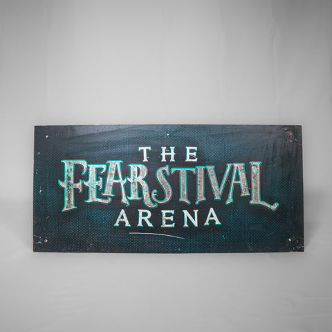 A landscape orientated sign which has a dark teal background. The logo for The Fearstival Arena is in the middle in a grey/white mottled colour scheme. Fearstival is outlined in an electric blue.