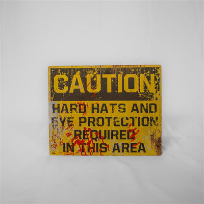 A fake caution sign from inside the Creek Freak Massacre attraction. It is a yellow sign with a brown/black text on top with a caution warning. Printed on top are rust and blood effects.