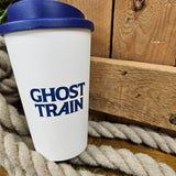 A white coffee tumbler with a blue lid and ghost train logo