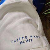A photo of the embroidered text on the bottom right of the hoody. The thread is navy blue and reads "Thorpe Park est 1979".