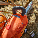 A photograph of the chainsaw handle, it is orange with a grey handle on top, embroidered button which says "press here" and text reading Thorpe Park