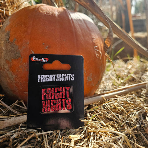 A black square pin badge with the words Fright Nights in the middle filled with a red glitter