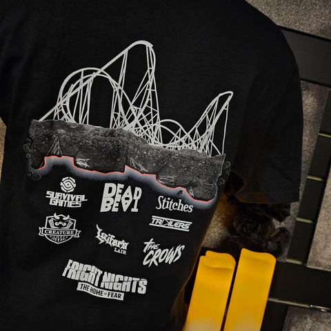 The back of a black short sleeved t-shirt. There is a printed design of Hyperia's skyline (in white), rockwork with a glowing red line underneath and the attraction logos in off white under that.