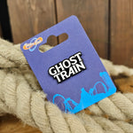 A pin badge which is a black metal base and a white infilled resin which says Ghost Train in the shape of the attraction logo