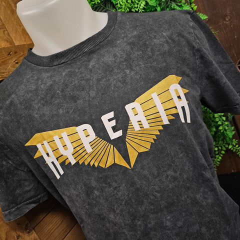 A grey t-shirt with a mottled texture. In the middle is a gold set of wings with the Hyperia logo printed in white.