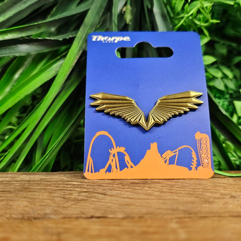 A pin badge, it is a set of metal wings in a brushed bronze colour. 