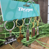 Collection of keychains with various logos on a green surface