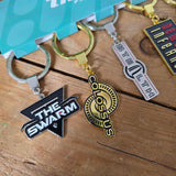 Collection of keychains with various logos on a wooden surface
