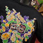 A close up of the artwork, it is green. yellow and purple splats with instruments and the mardi gras logo in the middle!