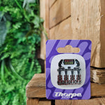 A pin badge shaped like the front car of Nemesis Inferno. It has four seats along the bottom with black backs and red harnesses, and the supporting structure above in dark grey. The ride logo is at the top centred over the middle two seats.