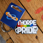 A keyring shaped like the Thorpe Pride logo, it is silver with a white and coloured inlay