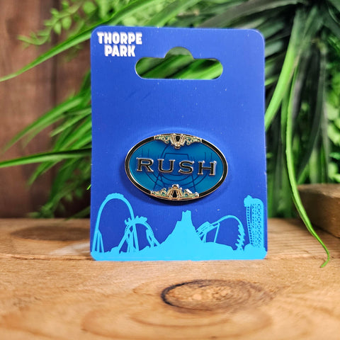 A logo pin, oval shaped with a translucent blue infill. In the middle is the word Rush in gold.