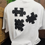The three printed jigsaw pieces on the back of the white t-shirt. The print is in black