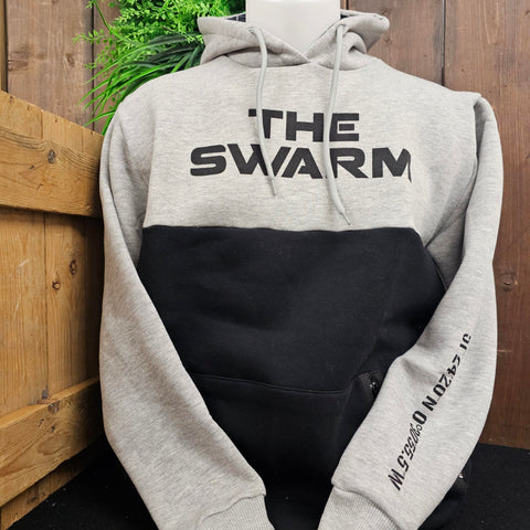 A two tone hoody, with a light grey top and sleeves, and a black bottom half. There is a THE SWARM logo printed in black across the chest and ride co-ordinates printed on the sleeve