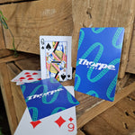 A photograph of playing cards, the backs of which are blue with a teal coaster track pattern and the Thorpe Park logo in white in the centre. The fronts are a standard deck of cards.