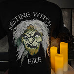 A black t-shirt with a green witches face in the middle. The phrase Resting Witch Face is around it.