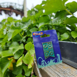 A photograph of the pin badge in front of the rollercoaster Colossus and some green foliage.