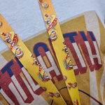 A photograph of the lanyard hanging on a bust on top of the Cannonball T-Shirt. It shows the middle of the lanyard as it begins to fade to orange towards the top. 