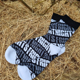 A photograph of a pair of socks. They are black and white with the words fright nights across them. The toes and heel are white.