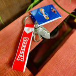 A photo of the keyring, it has a red strap with the words Stealth on it, and two charms - a metal clip embossed with the logo and a keyring clip