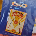 A photo of the magnet, it shows the Stealth Cannon Ball artwork, and is on a royal blue backing card. The artwork itself is red and orange with blue highlights and shows a person being shot out of a cannon forming the track shape of Stealth.