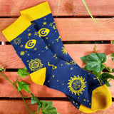 A photo of a pair of socks. The socks are royal blue, with vibrant yellow ankles, toes and heel areas. In the middle of the blue are yellow constellation symbols.