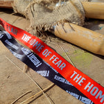 A photograph of a lanyard, the underside is red and says The Home of Fear in a silver text, the other side is black with the Fright Nights logo