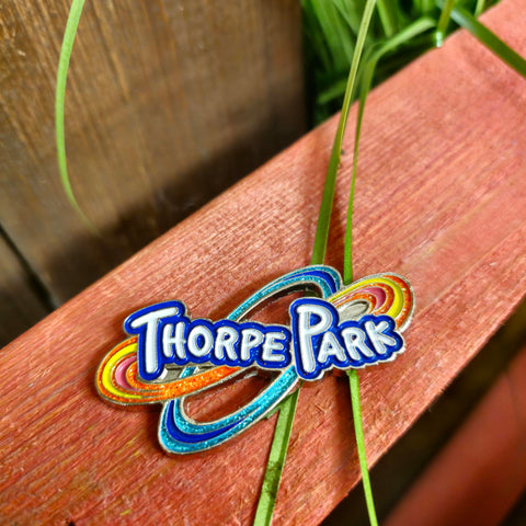 The Thorpe Park logo as a metal magnet, the infiinity loops behind are filled with orange and blue glitter