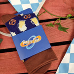A photograph of a pair of socks in their packaging. It has brown and dark blue fabric, and is wrapped in a cardboard sleeve (also blue) which has the Thorpe Park logo on.