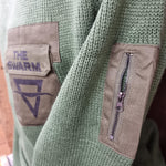 A close up of the zipped pocket on the arm of the jumper, and printed logo on the popper pocket on the chest.