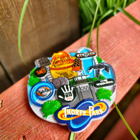 A photo of the magnet, it has small cartoon versions of each coaster along with the ride logos in a circular disk at the top. At the bottom on a navy background is the Thorpe Park logo